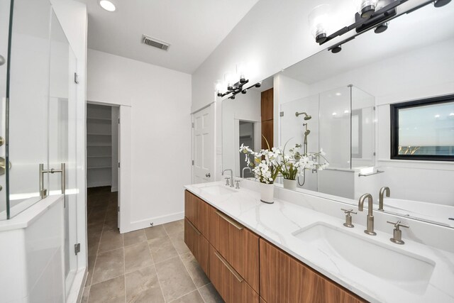 bathroom featuring double vanity, visible vents, a shower stall, and a sink