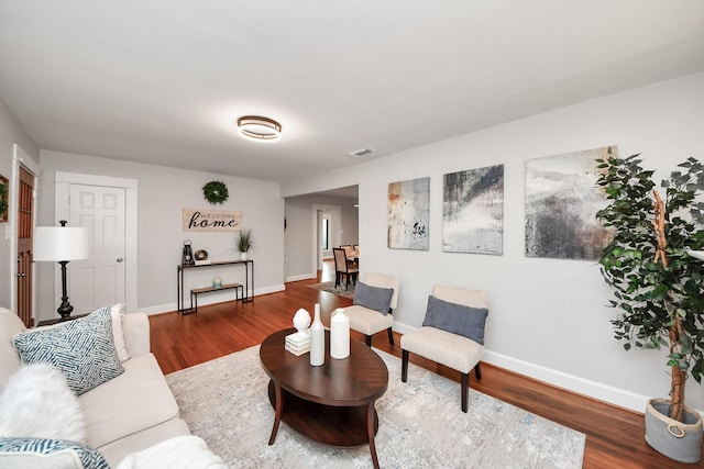 living room with visible vents, baseboards, and wood finished floors