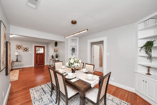 dining room with built in features, visible vents, baseboards, and light wood-style flooring