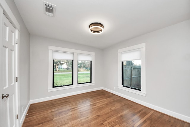 empty room featuring visible vents, baseboards, and wood finished floors