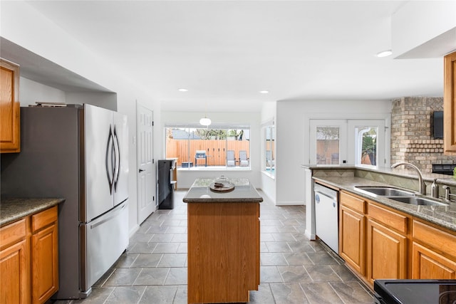 kitchen featuring backsplash, a kitchen island, dishwasher, freestanding refrigerator, and a sink