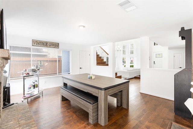 dining space featuring stairs, an inviting chandelier, visible vents, and dark wood-style flooring