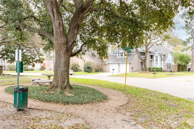 exterior space featuring a residential view, an attached garage, concrete driveway, and a front yard