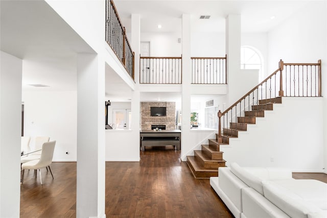 foyer with visible vents, baseboards, stairway, a towering ceiling, and hardwood / wood-style flooring