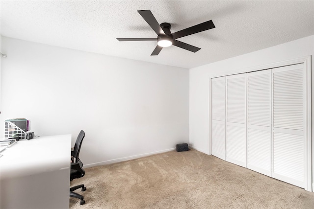 unfurnished office with baseboards, a textured ceiling, carpet, and a ceiling fan