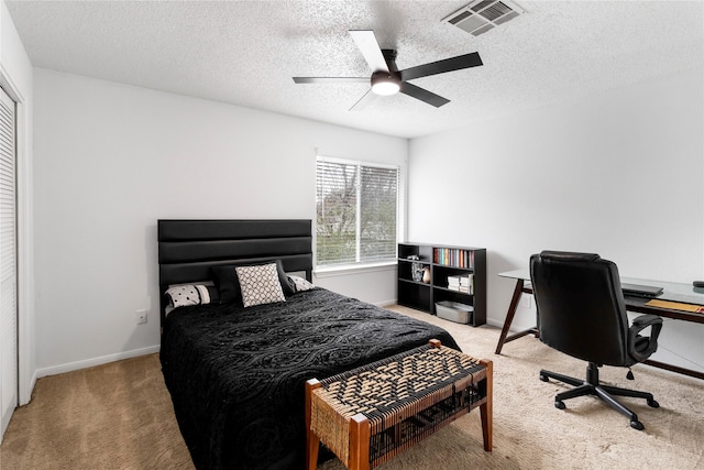 carpeted bedroom with visible vents, baseboards, a textured ceiling, and ceiling fan