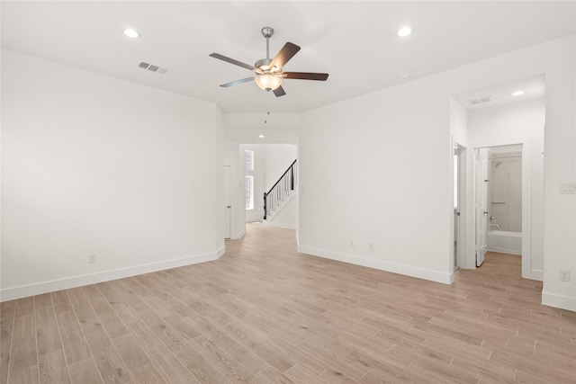 empty room with visible vents, light wood-style flooring, stairs, and baseboards