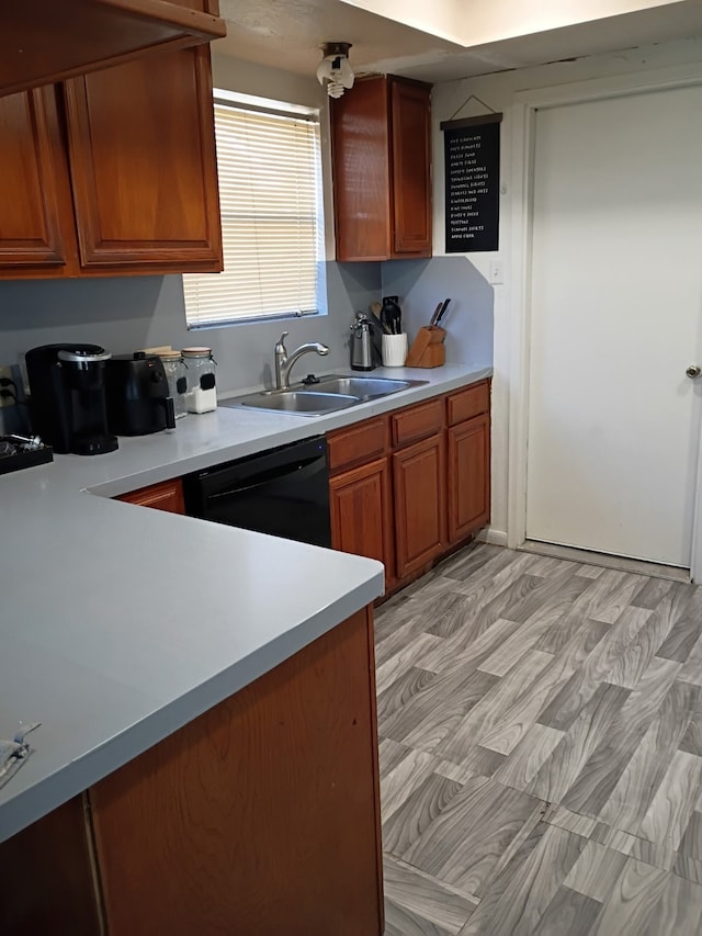 kitchen with light countertops, black dishwasher, brown cabinets, and a sink