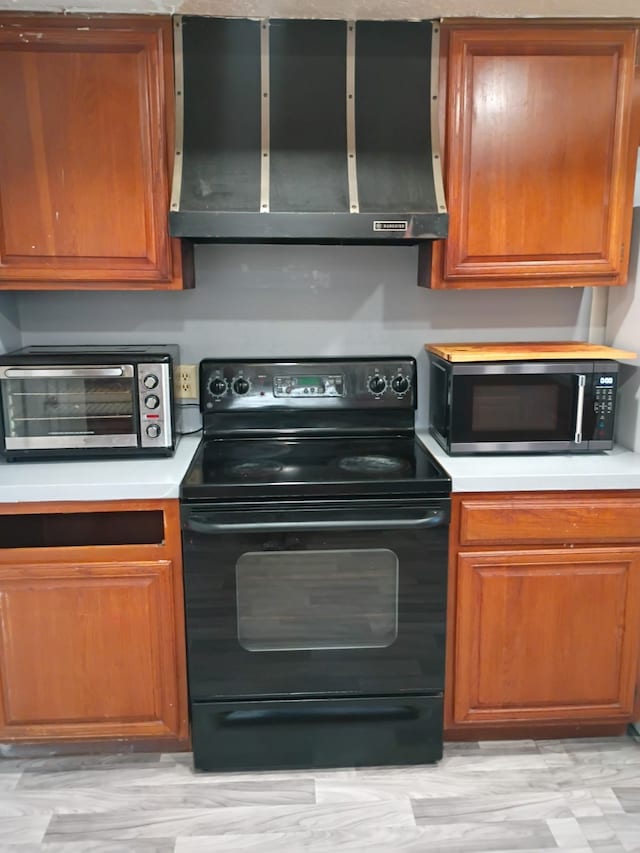 kitchen featuring stainless steel microwave, black range with electric cooktop, ventilation hood, brown cabinetry, and light countertops