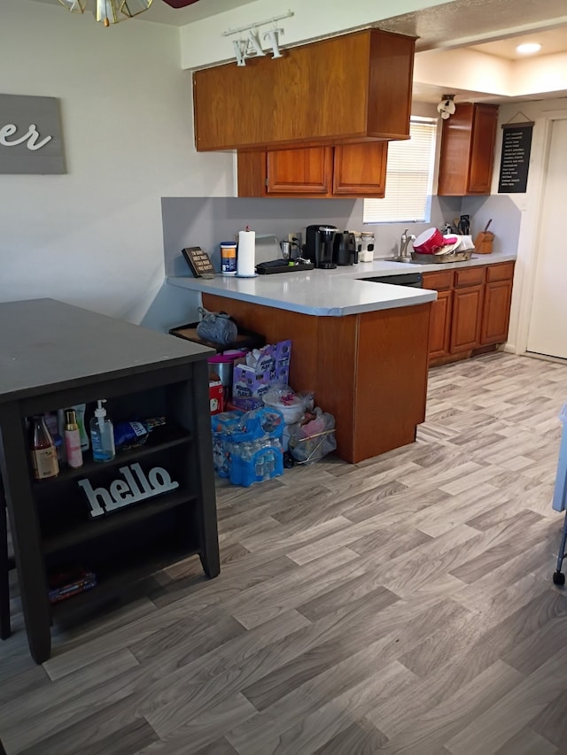 kitchen with brown cabinets, open shelves, light wood-style floors, a peninsula, and light countertops