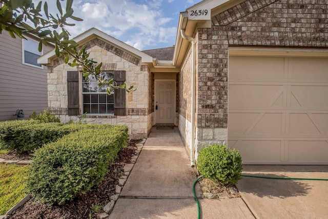 property entrance with brick siding, stone siding, and a garage