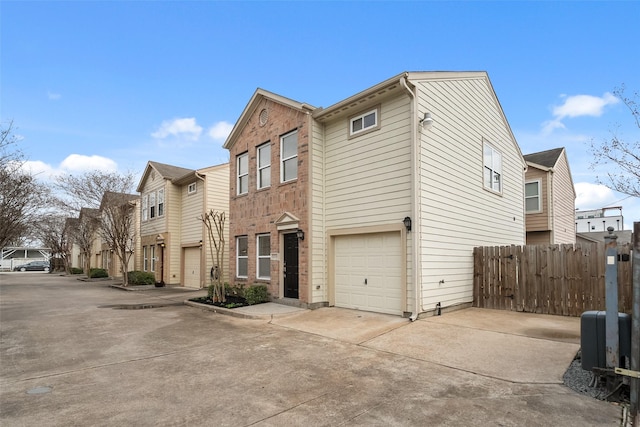 exterior space featuring concrete driveway, a garage, fence, and a residential view