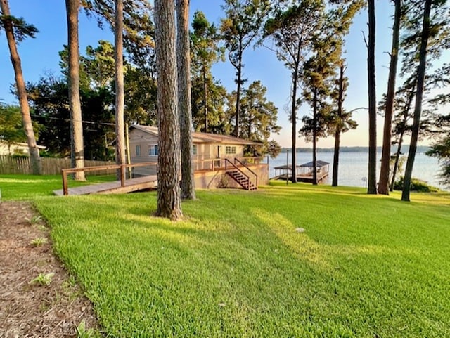 view of yard featuring a dock, fence, and a water view