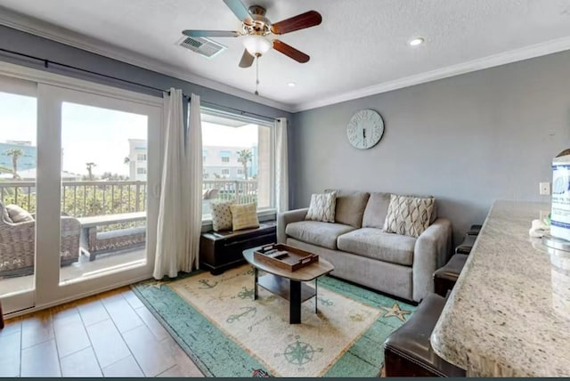 living room featuring a ceiling fan, visible vents, recessed lighting, ornamental molding, and a textured ceiling