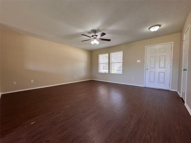 unfurnished room with a textured ceiling, baseboards, dark wood-type flooring, and a ceiling fan