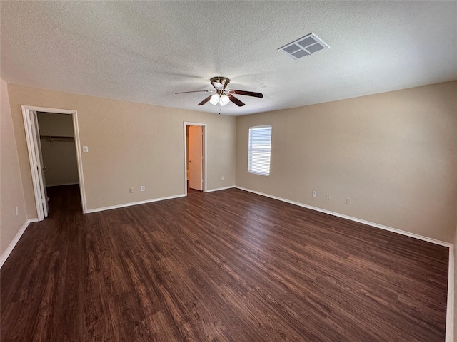 spare room with ceiling fan, visible vents, baseboards, and dark wood-style floors