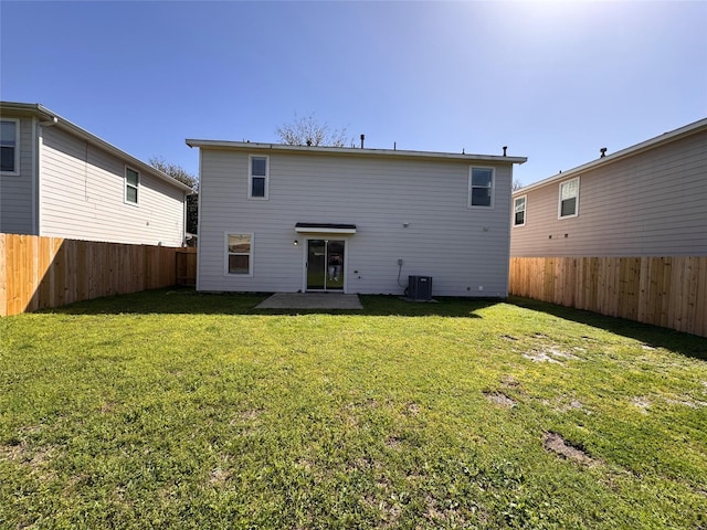 rear view of house featuring a lawn, central AC, and a fenced backyard