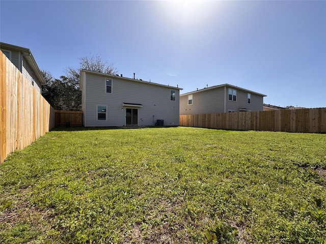 rear view of property featuring a lawn and a fenced backyard