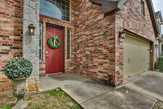 view of exterior entry featuring brick siding, concrete driveway, and an attached garage