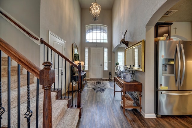 entrance foyer featuring visible vents, dark wood-type flooring, baseboards, a high ceiling, and arched walkways