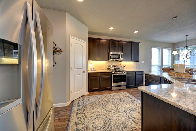 kitchen with a notable chandelier, dark wood-style flooring, stainless steel appliances, and a sink