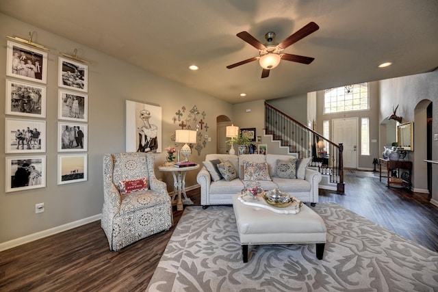 living room with stairs, wood finished floors, arched walkways, and baseboards