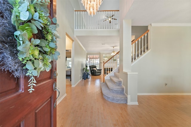 foyer with baseboards, wood finished floors, stairs, and ornamental molding