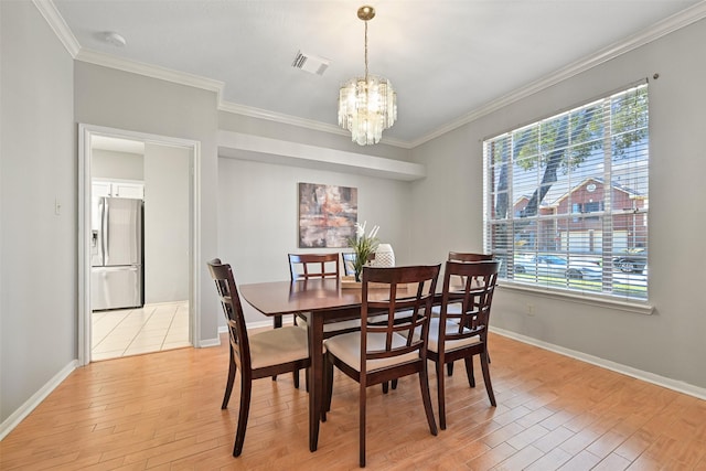 dining room featuring visible vents, light wood-style flooring, crown molding, and an inviting chandelier