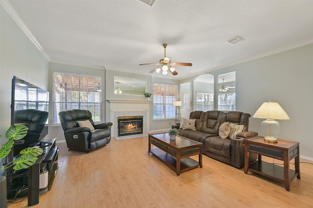 living room featuring visible vents, light wood-type flooring, baseboards, and ornamental molding