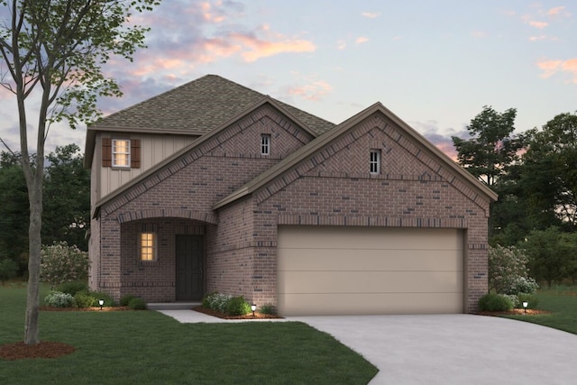 view of front facade featuring a garage, a yard, brick siding, and driveway