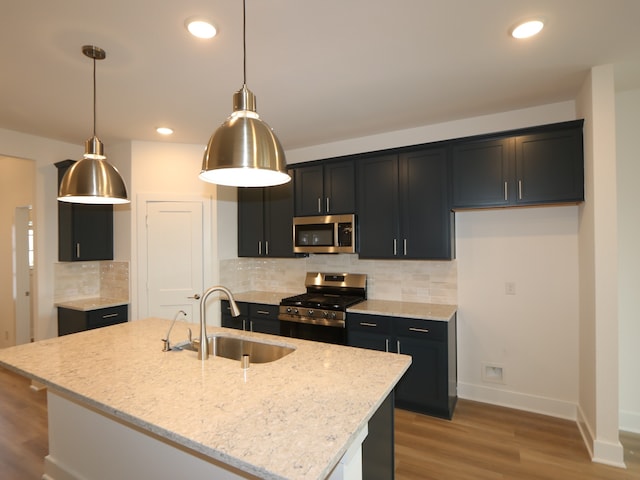 8035 Kay Harbor Dr, Cypress, TX 77433 - kitchen with appliances with stainless steel finishes, light wood-type flooring, dark cabinets, light stone counters, and decorative backsplash