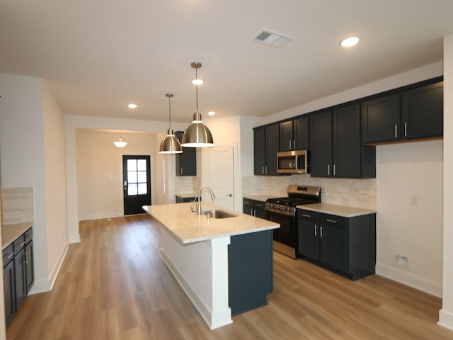 8035 Kay Harbor Dr, Cypress, TX 77433 - kitchen featuring stainless steel appliances, backsplash, light wood-style flooring, dark cabinetry, and light stone countertops