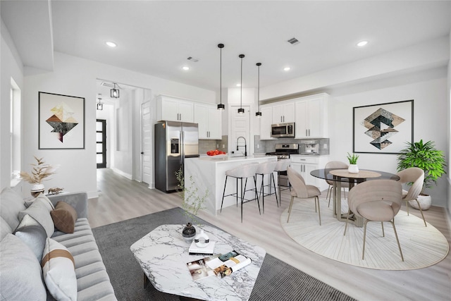 living room featuring light wood-style flooring, recessed lighting, and visible vents