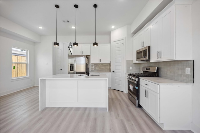 kitchen featuring light wood-type flooring, white cabinets, stainless steel appliances, and light countertops