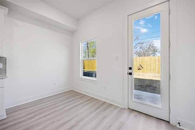 doorway featuring light wood finished floors and baseboards