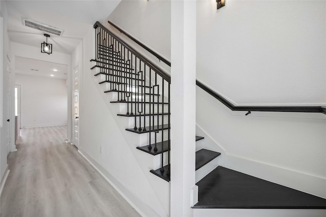 stairway with visible vents, baseboards, and wood finished floors