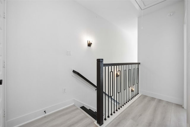 staircase with attic access, wood finished floors, and baseboards