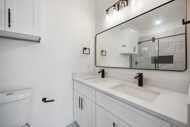 bathroom with double vanity, a shower stall, toilet, and a sink