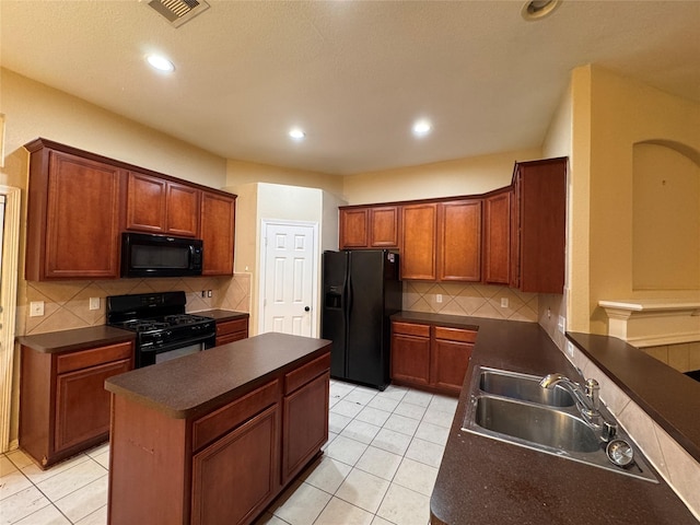 kitchen with dark countertops, visible vents, a kitchen island, black appliances, and a sink