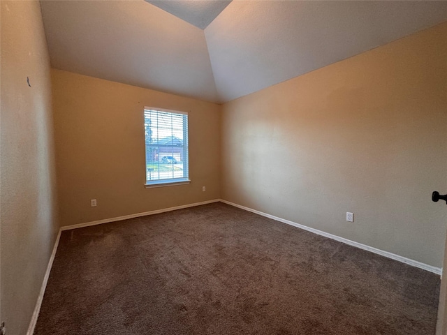 unfurnished room with baseboards, dark carpet, and vaulted ceiling