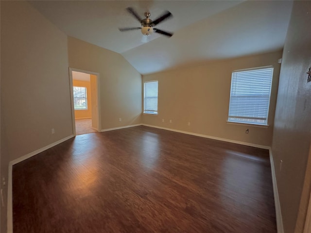 spare room featuring baseboards, dark wood-type flooring, ceiling fan, and vaulted ceiling