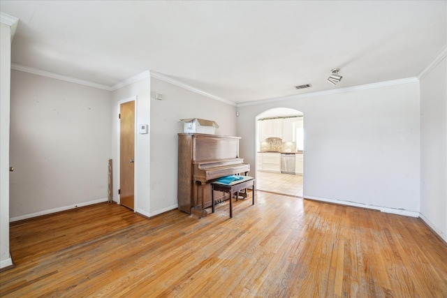 interior space with visible vents, light wood-style flooring, crown molding, and baseboards