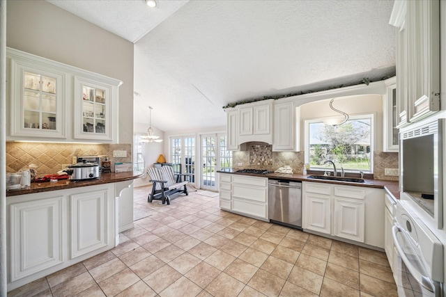 kitchen with a sink, dark countertops, appliances with stainless steel finishes, and vaulted ceiling