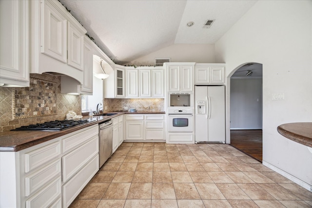 kitchen featuring dark countertops, visible vents, vaulted ceiling, arched walkways, and stainless steel appliances