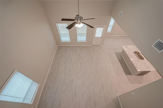 interior space featuring visible vents, a ceiling fan, baseboards, and wood finished floors