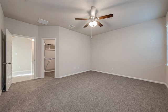 unfurnished bedroom featuring a spacious closet, visible vents, ceiling fan, baseboards, and carpet floors