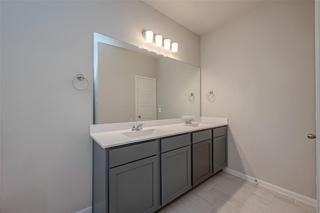 full bath featuring double vanity, baseboards, and a sink