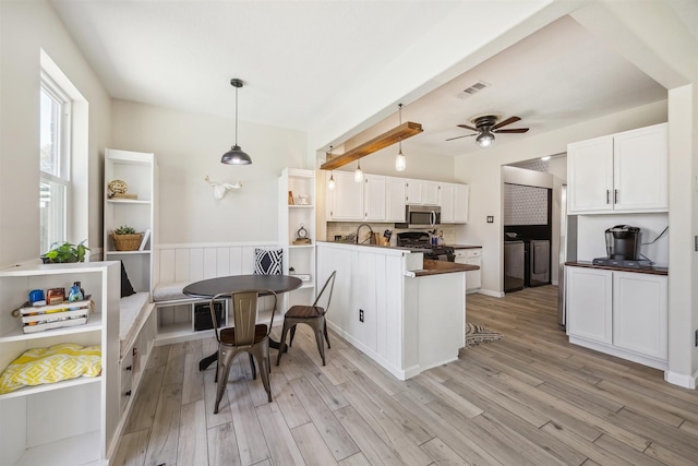 kitchen featuring visible vents, white cabinets, gas range, stainless steel microwave, and light wood-type flooring