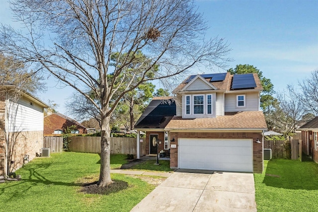 traditional-style home featuring fence, a front lawn, concrete driveway, brick siding, and roof mounted solar panels