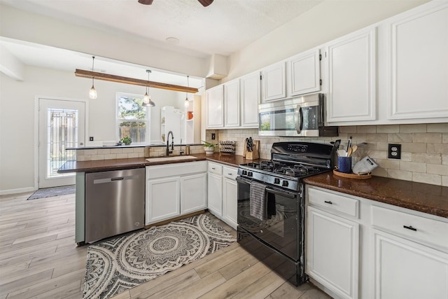 kitchen with a sink, backsplash, appliances with stainless steel finishes, a peninsula, and light wood finished floors